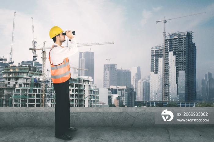 Architect looking at the construction site with binocular