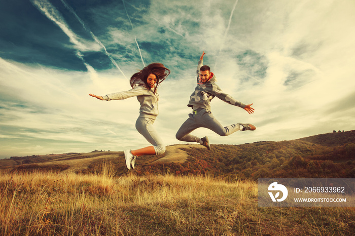 Happy young couple jump in the air in nature