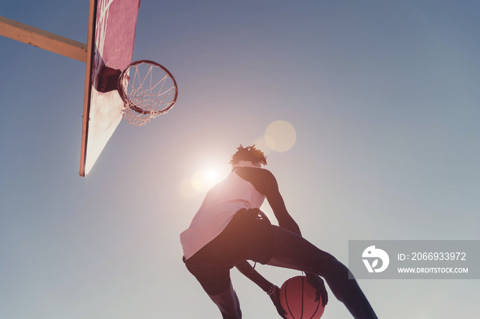 Basketball street player making a rear slam dunk at sunset- Sporty black man playing basketball outdoor