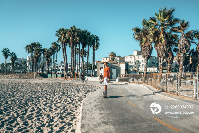 Young man riding a one wheel down the Venice beach in Los Angeles, California. Beautiful summer vibes.