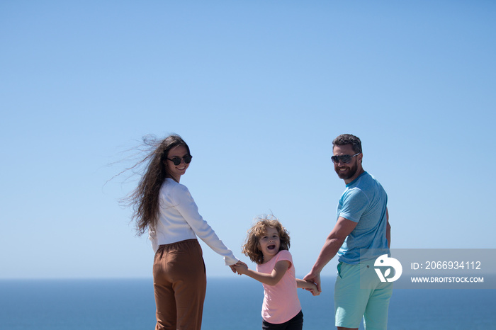 Weekend family concept. Happy family holidays. Joyful father, mother, baby son walk of sea sand beach. Active parents and people outdoor activity on summer vacations with children.