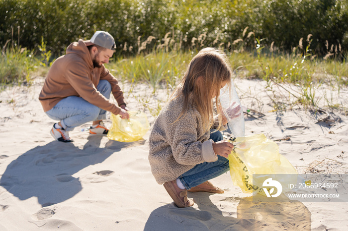 happy family activists collecting plastic waste on beach. Volunteers help to keep nature clean up and pick up garbage.