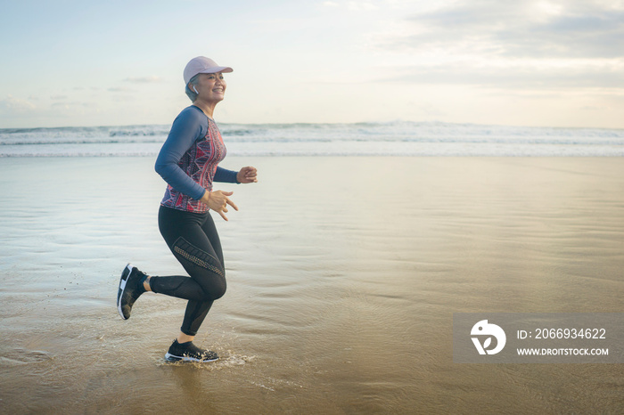 fit and happy middle aged woman running on the beach - 40s or 50s attractive mature lady with grey hair doing jogging workout enjoying fitness and healthy lifestyle