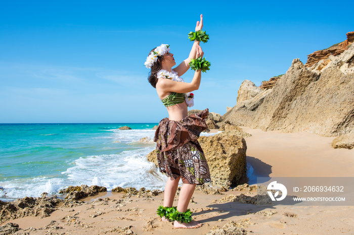 Hawaiian woman enjoys hula dancing on the beach barefoot wearing traditional costume