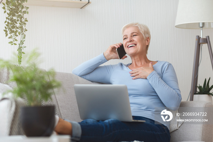 Joyful elderly business lady talking by smartphone