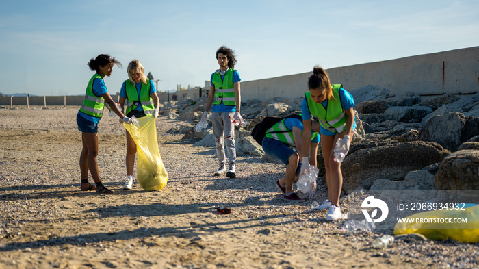 People cleaning up the beach, volunteers collecting the waste on the coast line, young students working in team aware of the pollution produced by the plastic industry