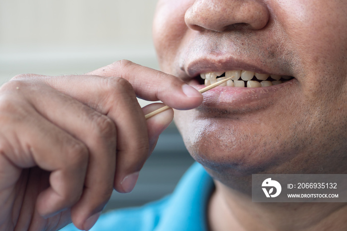 man with crooked teeth using toothpick, concept of oral care, tooth care, bad breath