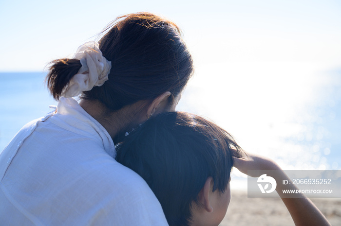 Back view of parent and child gazing out to sea