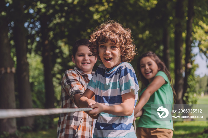 selective focus of cheerful kids competing in tug of war