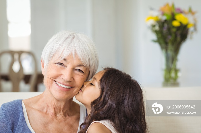 Granddaughter kissing grandmother on cheek in living room