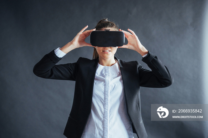 Happy woman on background in the studio gets the experience of using VR-glasses virtual reality headset