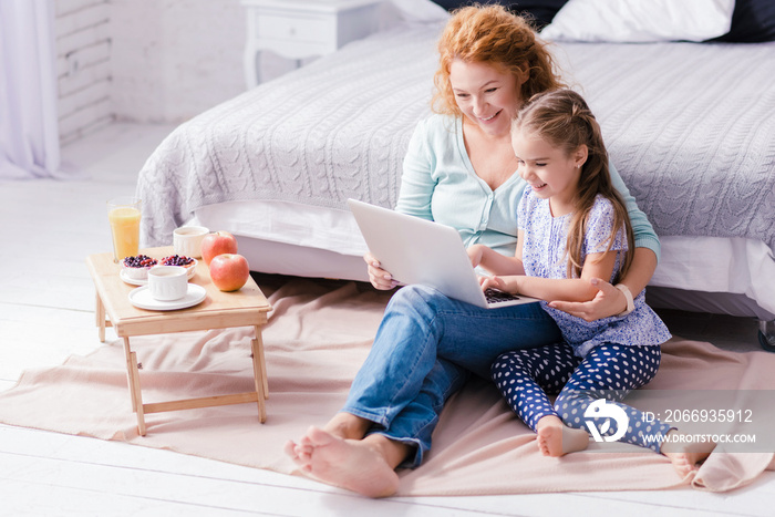 Girl sitting in front of the laptop with her grandmother