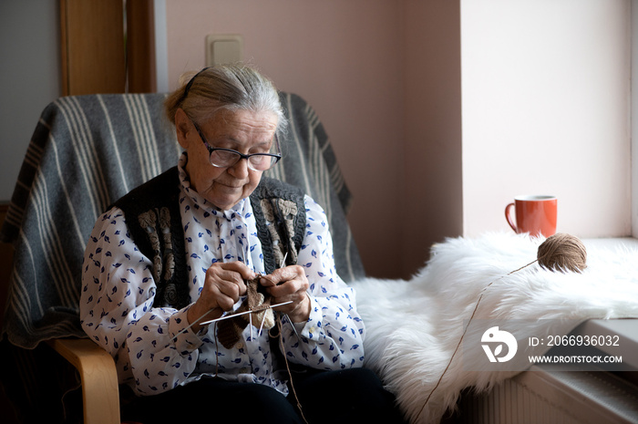 old woman knitting in a nursing home by the window