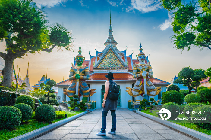 Traveler woman looking old temple in Wat Arun at evening sunset time, Popular famous landmark travel Bangkok Thailand, Tourist female on holiday vacation trip, Tourism beautiful destination place Asia