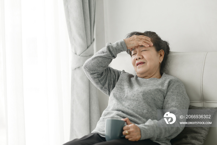Asian senior woman having headache at home, health care concept.