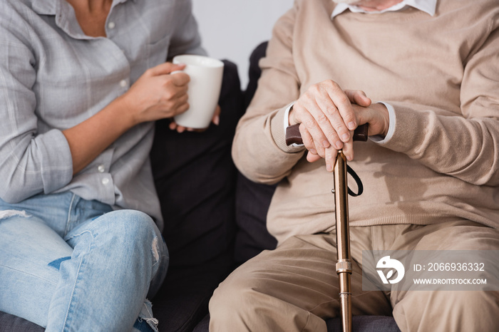 partial view of woman with cup of tea near aged father at home, banner