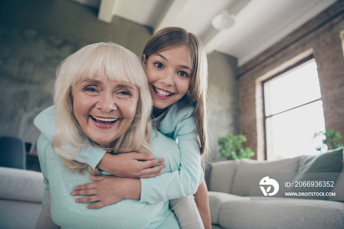 Low below angle view photo of two best friends people cute aged granny small grandchild girl hug piggyback playing funny game spend weekend together house indoors