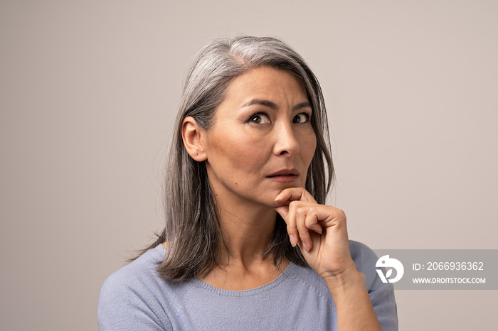 Adult Mongolian Woman with Gray Hair on a Gray Background.