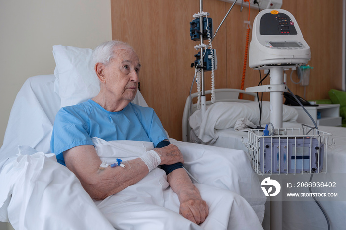 Elderly man in a hospital bed undergoing a blood pressure test