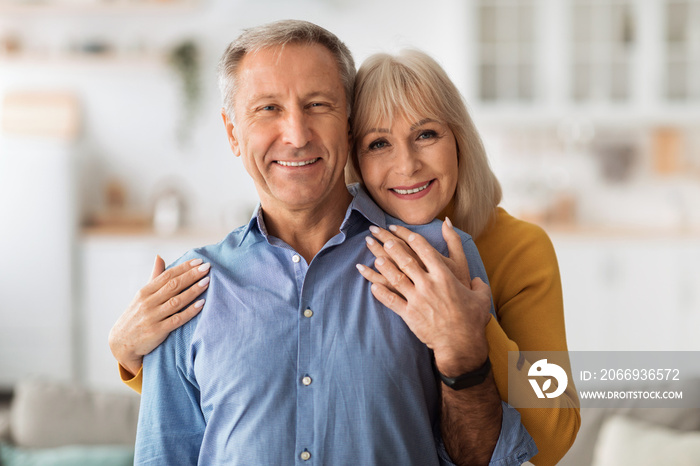 Senior Wife Embracing Husband Posing Together Standing In Kitchen