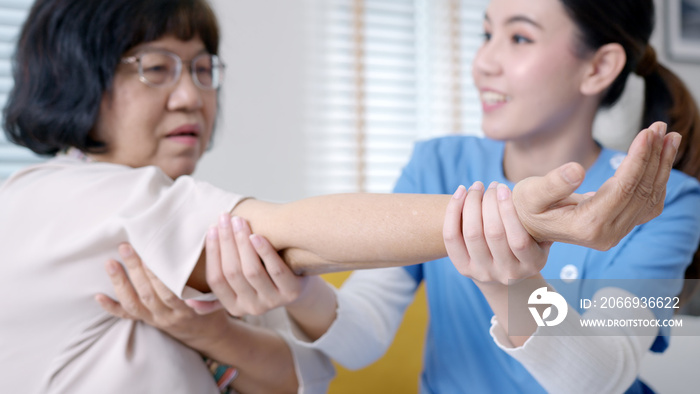 Young senior asia citizen female with scrubs nurse physiotherapy worker at home in rehabilitation therapy service for aging parents. Massage for older care, ache pain joints exercise in old people.