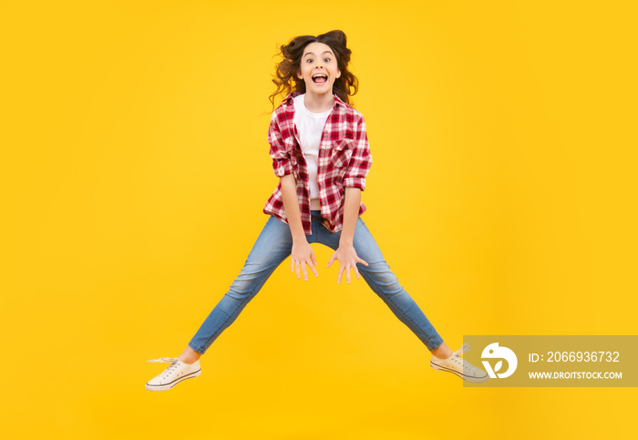 Amazed teenager. Excited teen girl. Full length overjoyed teenager kid girl 12 13 14 year in casual wear jumping old isolated on yellow background studio. Funny jump. Child in summer movement dress.