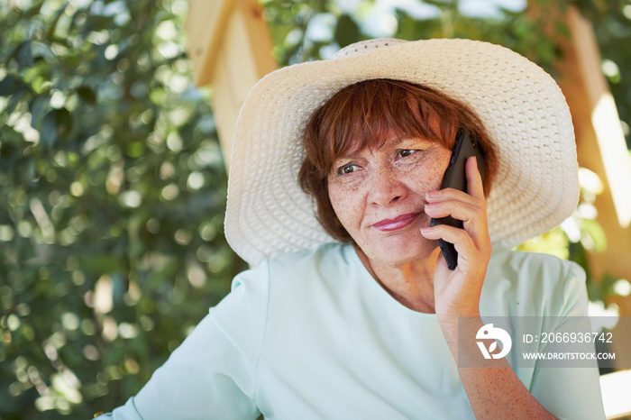 aged woman talking on the phone. old lady in the Park. Sunny day, happy mood. upset senior woman with phone