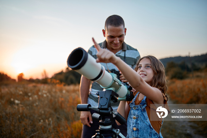 Father and daughter observing the sky with a telescope.