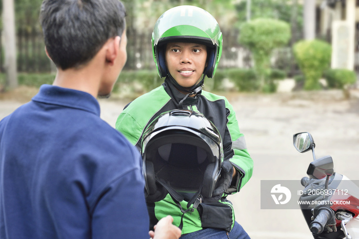 Portrait of asian motorcycle taxi driver giving the helmet