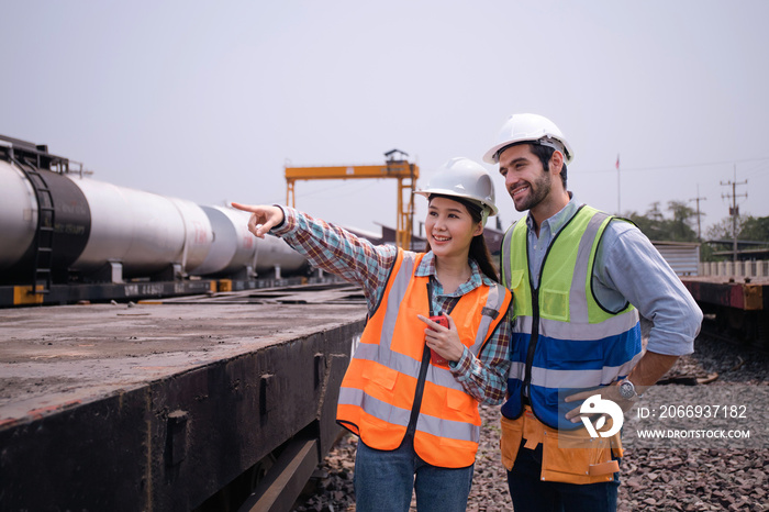 Oil rail transport specialist engineers are smiling checking the quality Planning discuss work at  site fuel train.South American,Middle East,Thai,Asia workers wearing PPE vests,pointing target.