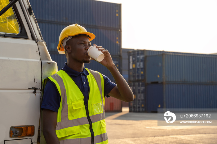 An African truck driver stood resting and smiling happily beside the truck. at the container warehouse