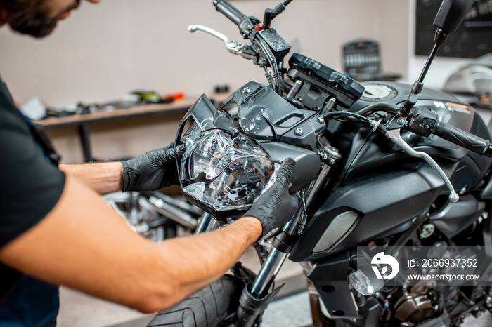 Worker repairing motorcycle headlight in the workshop