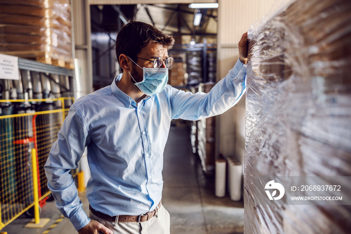 Full length of handsome smiling businessman having phone call with customer while walking in warehouse.