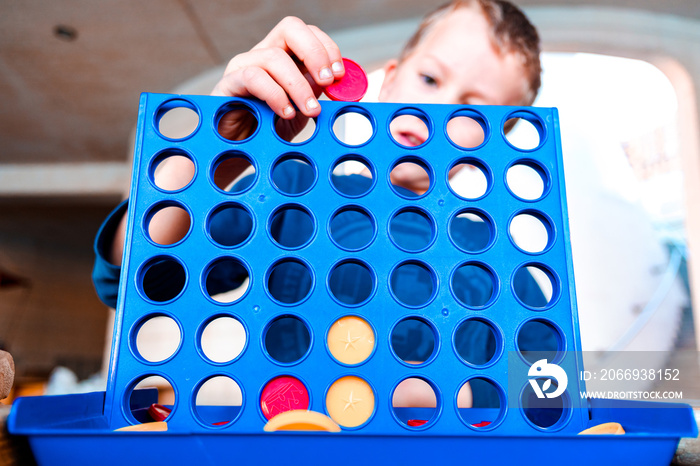 Child playing a traditional strategy game to form 4 chips row.