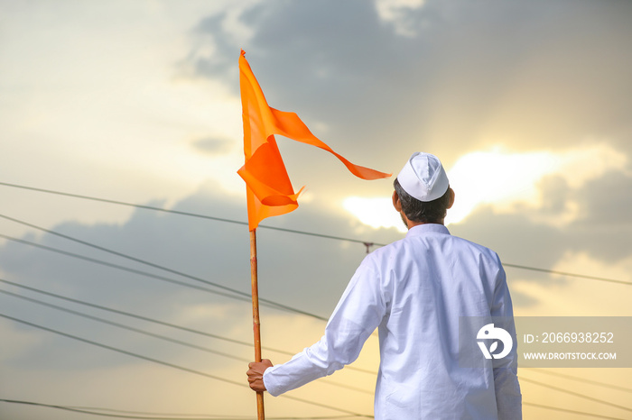 Young indian man (pilgrim) in traditional wear and waving religious flag.