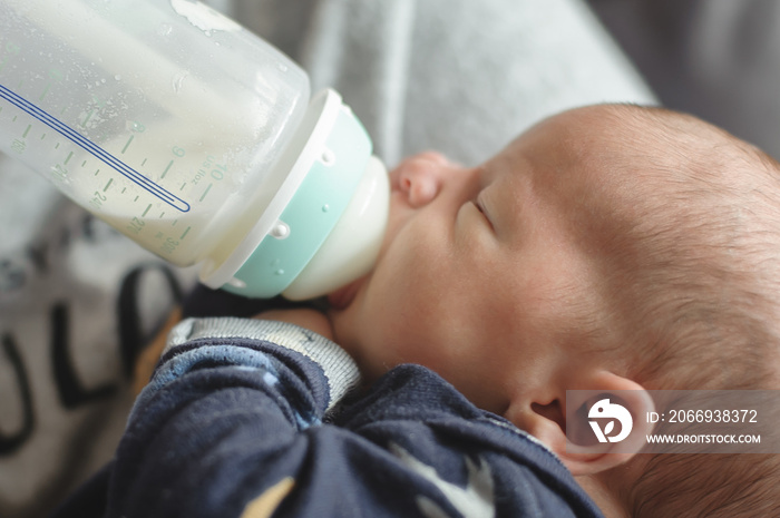 Close-up detail view of mother with love feeds her cute little baby with milk from a feeding bottle