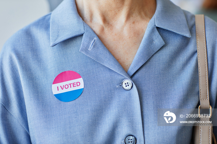 Close up of woman with I voted sticker on simple blue shirt, copy space