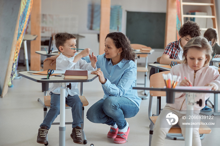 Afro american handsome teacher is explaning to little male student grammar rules