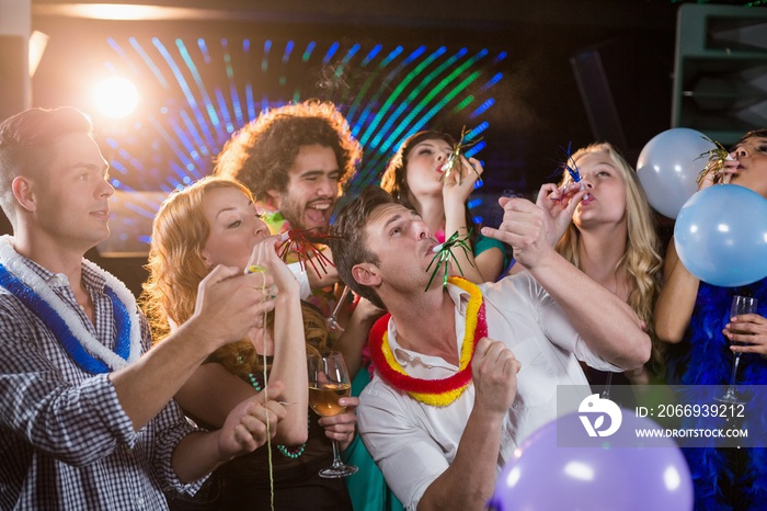 Group of friends blowing party horn in bar