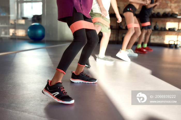 Close up of legs of kids working out using resistance band in gym. Sport, healthy lifestyle, physical education concept