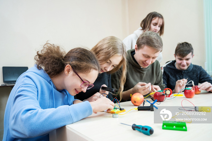 Diverse teenager pupils build robot, learn at table at STEM engineering science education class.