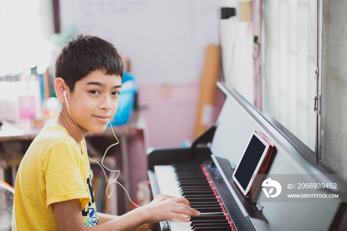 Little boy learning practicing piano online digital tablet