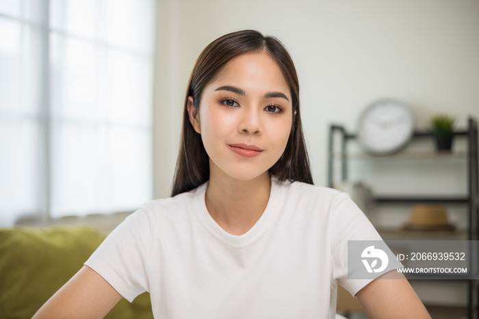 Young asian woman looking at camera video conference online sitting in living room at home. Business Woman looking at screen Meeting on social media live steam. Work, learning from home.