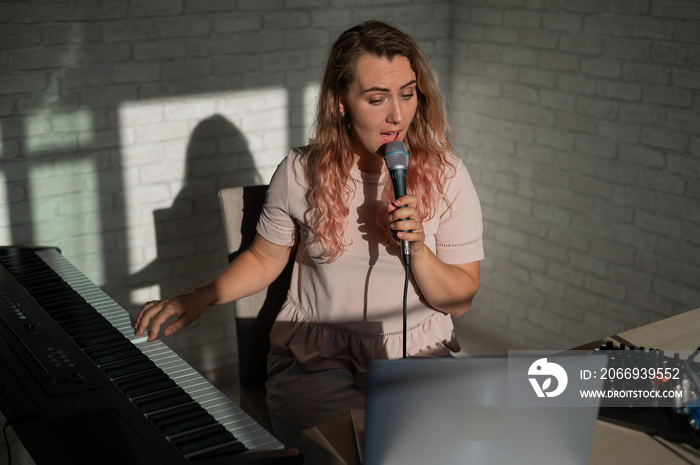 A young European woman sings into a microphone and accompanies on an electronic piano. The girl shoots a video blog. Remote vocal lesson. A female singing teacher conducts online classes.