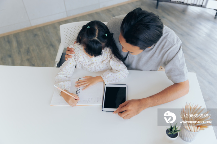 Attractive asian father teaching little child daughter learning studying doing homework at home, Family quality time and e-learning education concept