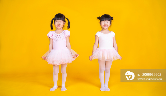 Portrait of little asian girls dreams of becoming ballerina in a pink tutu skirt isolated on yellow background. Happy young girl practise her dance. Education childhood toddler lifestyle concept