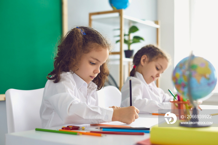 Back to school. Children schoolchildren write while sitting at the table in the classroom. Learning education development lessons for children.