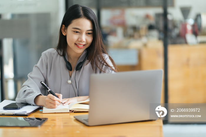 Beautiful Young Freelancer Woman Using Laptop Computer Sitting At Cafe Table. Happy Smiling Girl Working Online Or Studying And Learning While Using Notebook. Freelance Work, Business People Concept