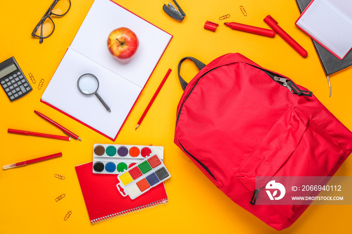 School backpack with stationery on color background