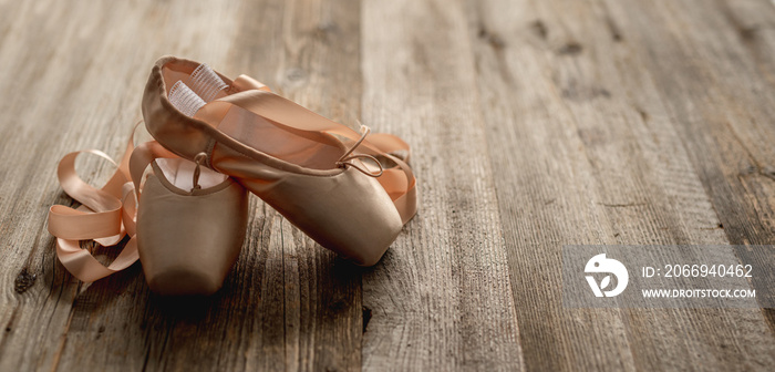 Pointe shoes with ribbons on wooden background